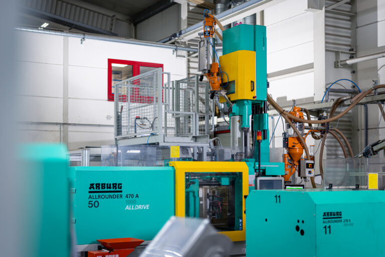 Eine moderne Spritzgussmaschine von Schröder und Heidler formt Kunststoffprodukte in einer hochmodernen Fabrikumgebung.
