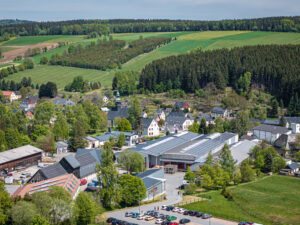 Eine Luftaufnahme zeigt die idyllische Landschaft mit Werkstätten und dem Betrieb von Schröder und Heidler für Kunststoff-Spritzguss.