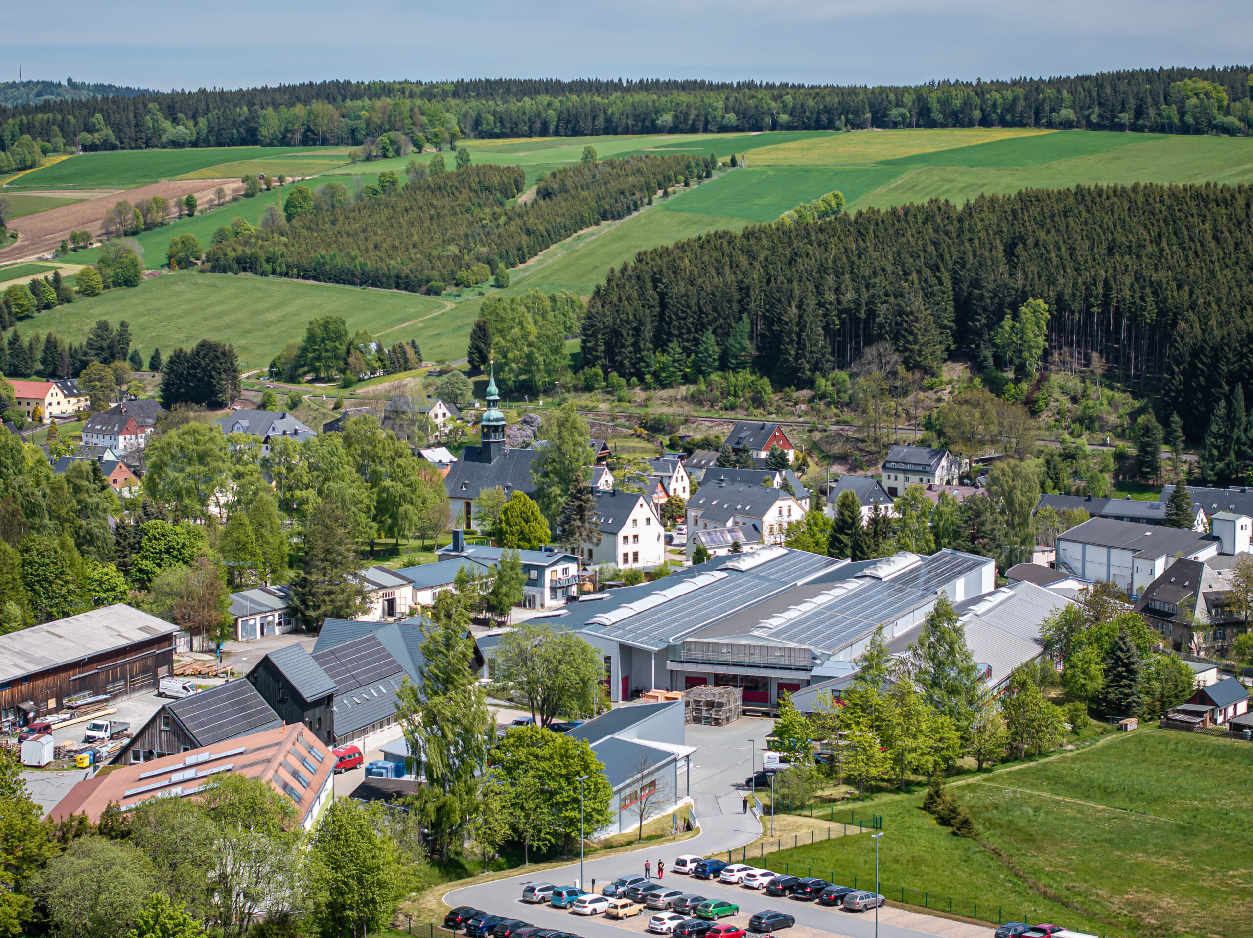 Eine Luftaufnahme zeigt die idyllische Landschaft mit Werkstätten und dem Betrieb von Schröder und Heidler für Kunststoff-Spritzguss.