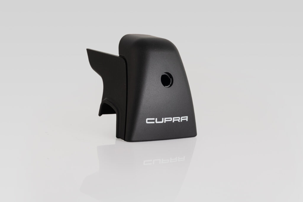 Ein schwarzes Kunststoffteil mit "CUPRA"-Logos, hergestellt durch Spritzguss bei Schröder und Heidler. | © Schröder + Heidler