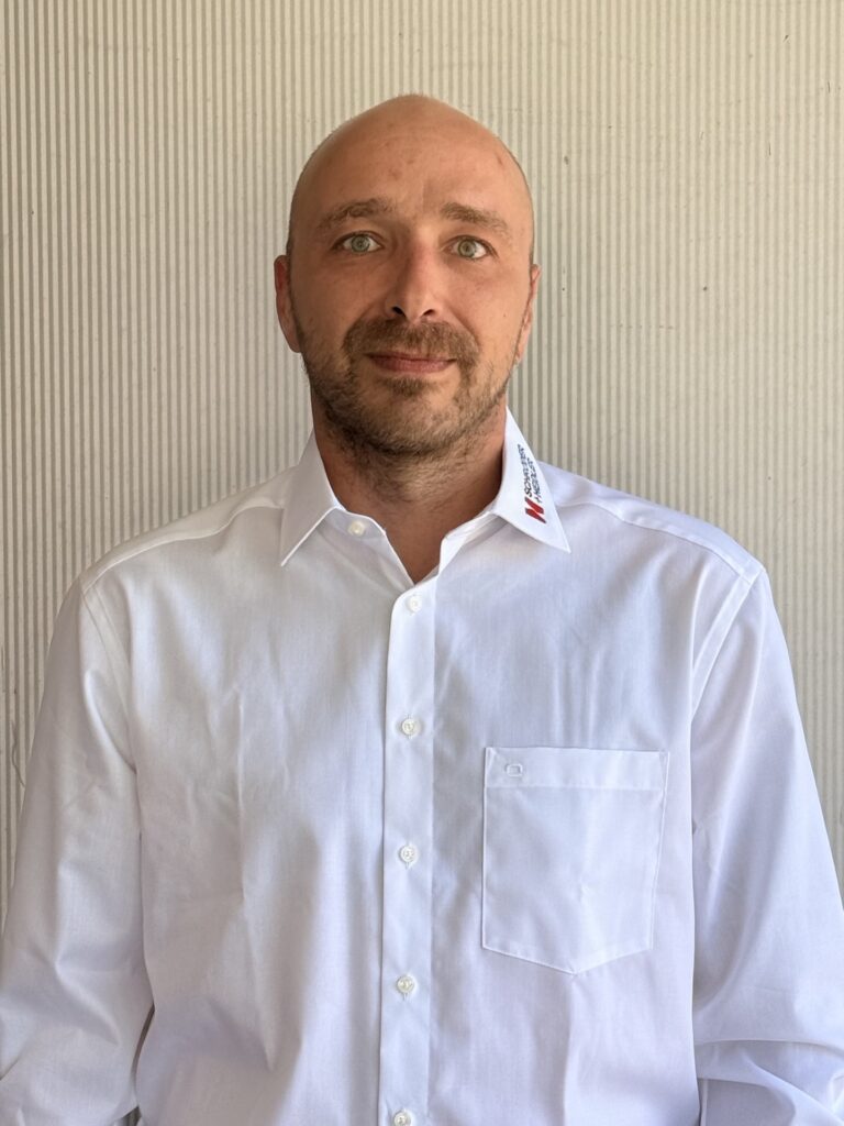 Kevin Viol steht in einem weißen Hemd vor einer Wand, repräsentiert Schröder und Heidler im Kunststoff-Spritzguss.